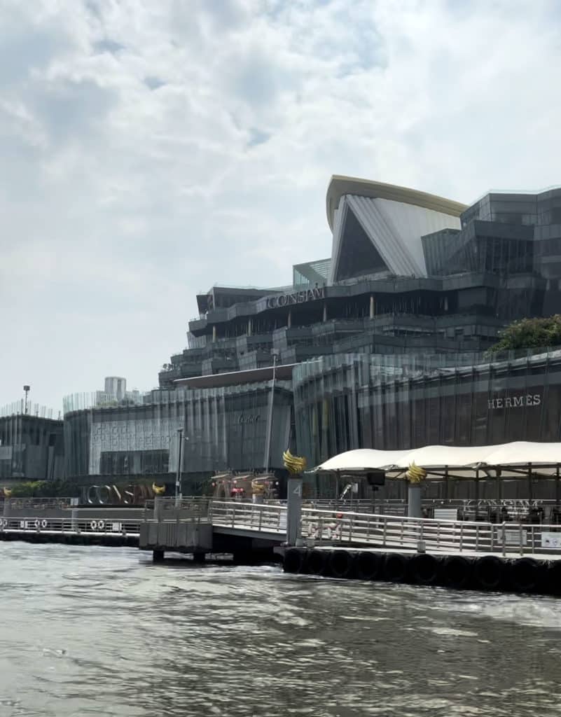 A picture of the Iconsiam mall viewed by boat. There is also the Hermes store showing and a dock.